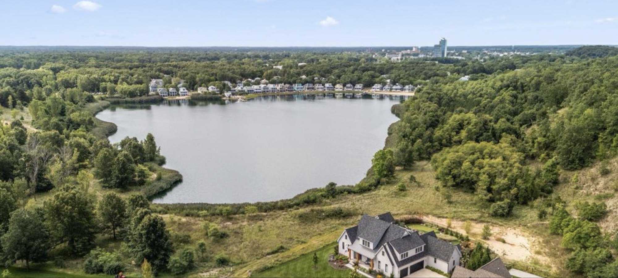 Lake Kai aerial — the private 26.2-acre lake at the heart of Indiana Dunes Club, with the Beachwalk community visible on the north shore and downtown Michigan City on the horizon.