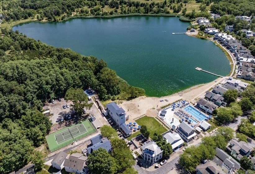 Beachwalk Resort amenities from above — clubhouse, tennis courts, and pool on the north shore of the adjacent lake. Indiana Dunes Club sits on the opposite shore of the same lake.